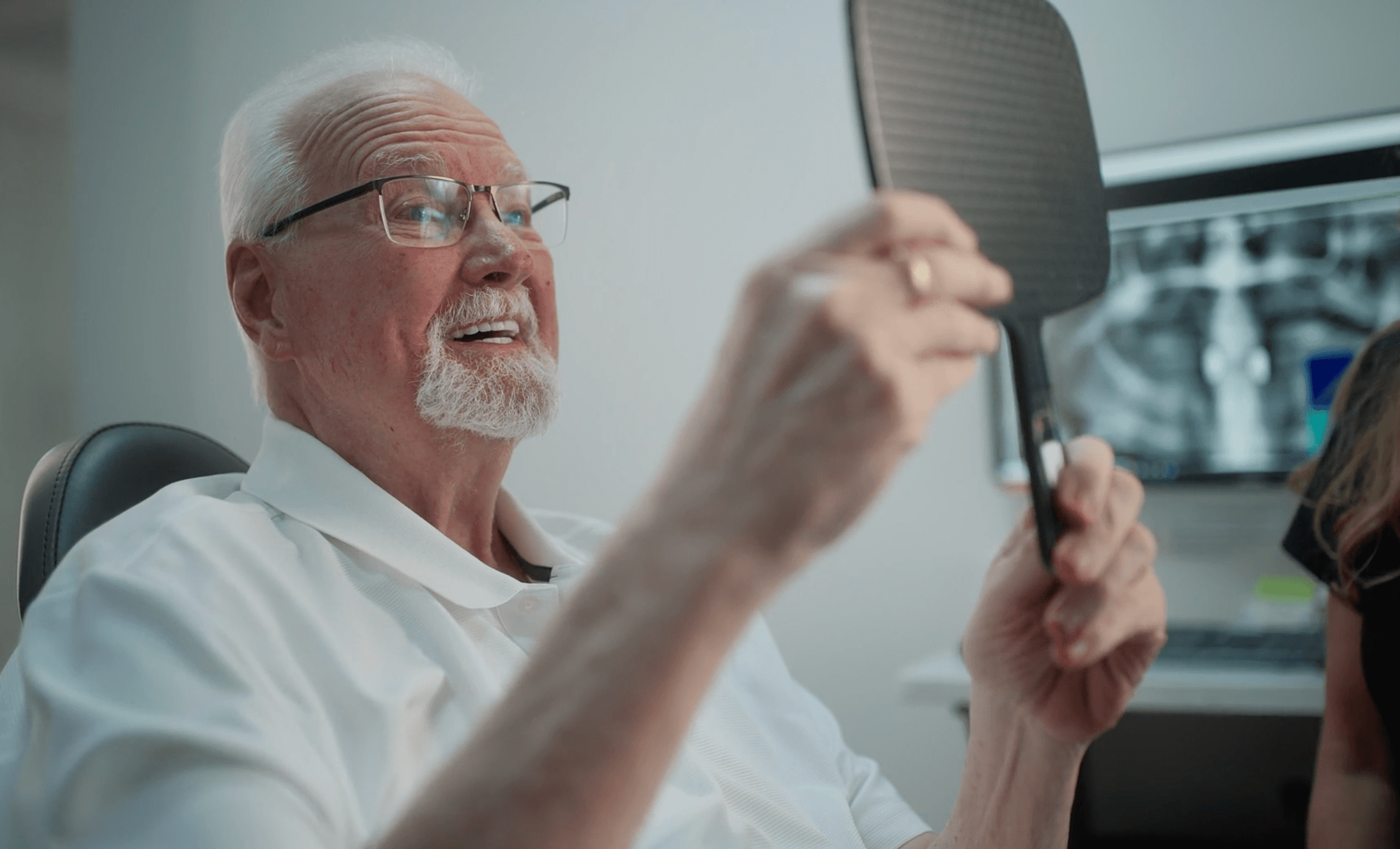 A patient looking at their smile in a hand mirror at St. Pete Family & Cosmetic Dentistry.